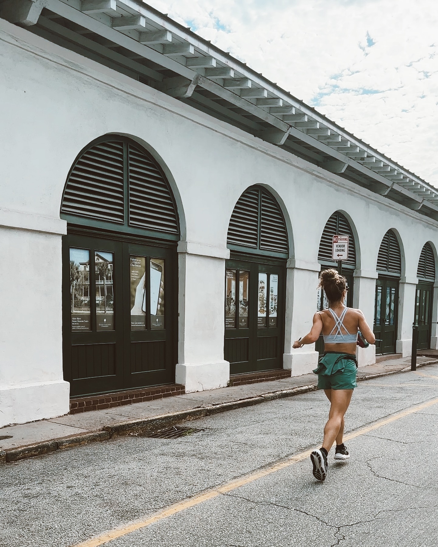 A woman running down a sunlit city street